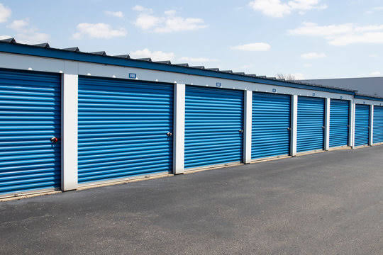 Row of drive-up storage units with blue roll-up doors